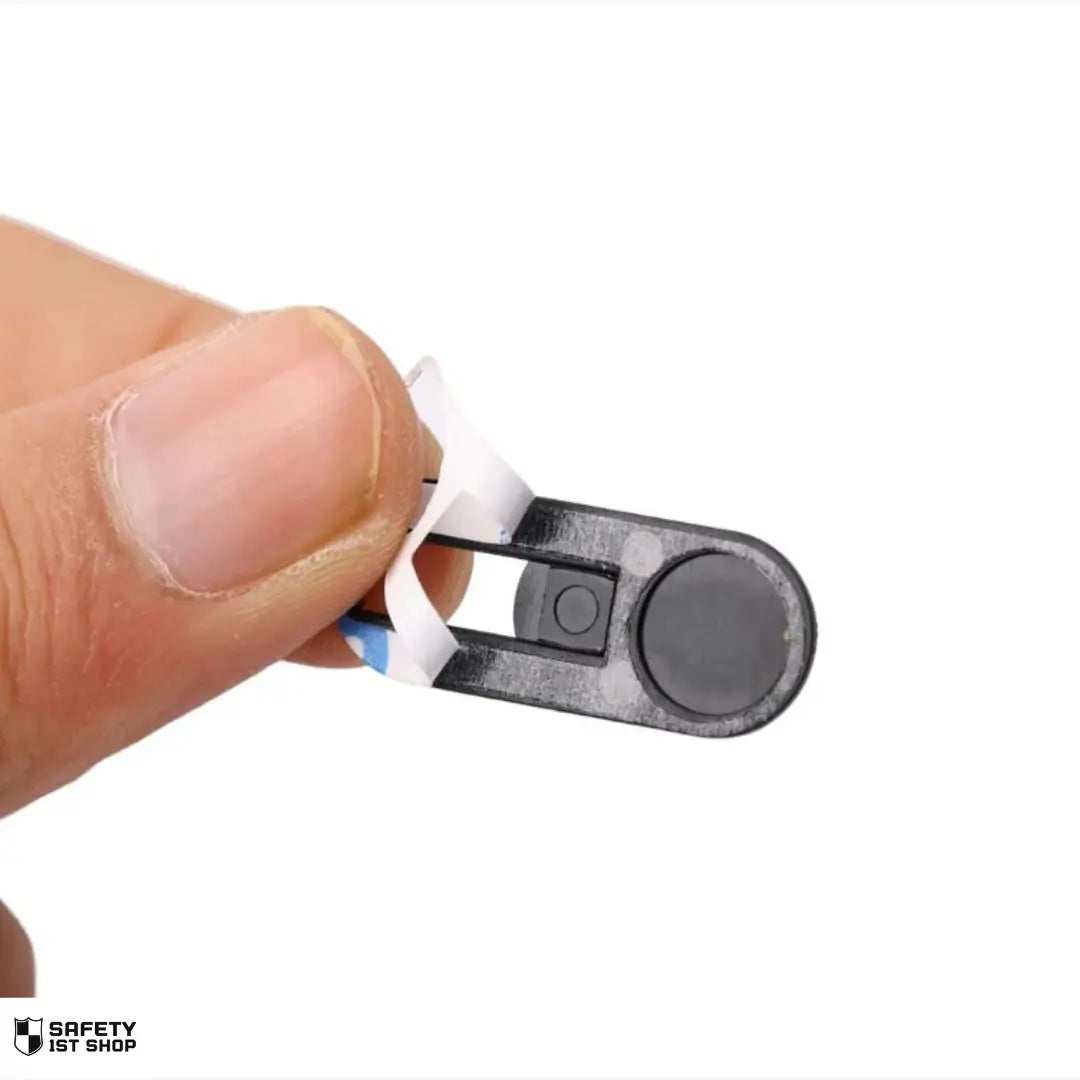 Hand holding black webcam privacy cover with adhesive strip partially peeled – showcasing easy installation