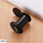 Close-up of matte black door viewer on beige laminated surface, elegant and subtle design with fine details visible