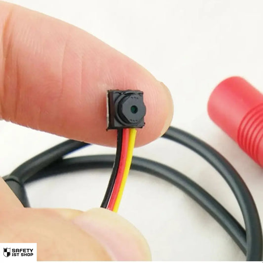 Mini surveillance camera lens shown on fingertip – ultra compact with cable, white background