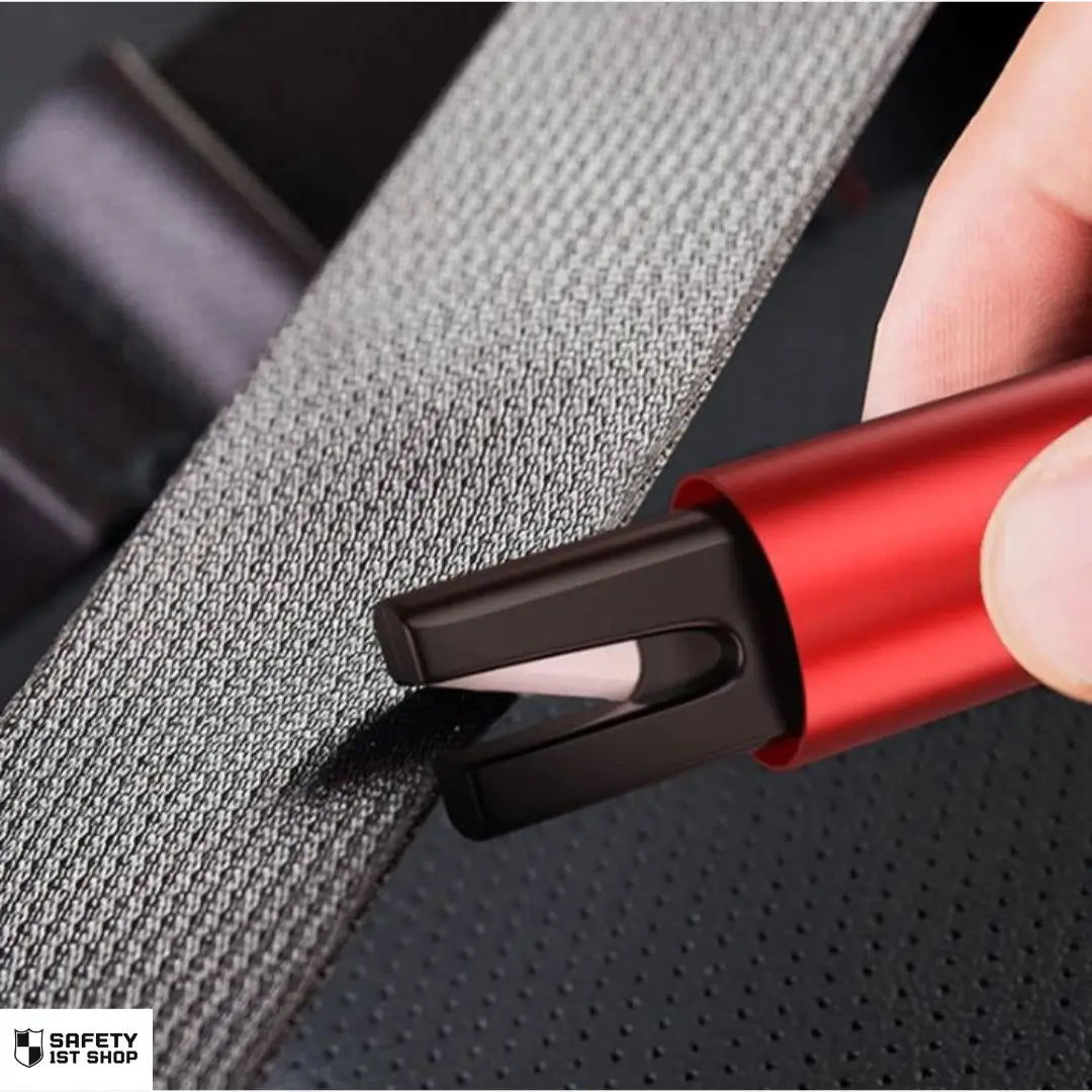 Hand holding red emergency car hammer cutting black seatbelt – safety blade in use demonstration